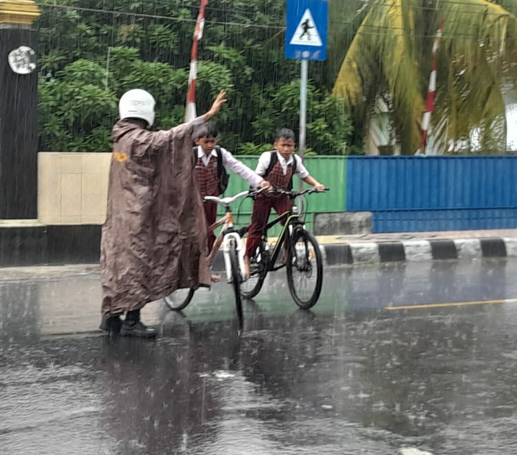 Hujan Tak Halangi Polsek Gerung Atur Lalu Lintas Sekolah